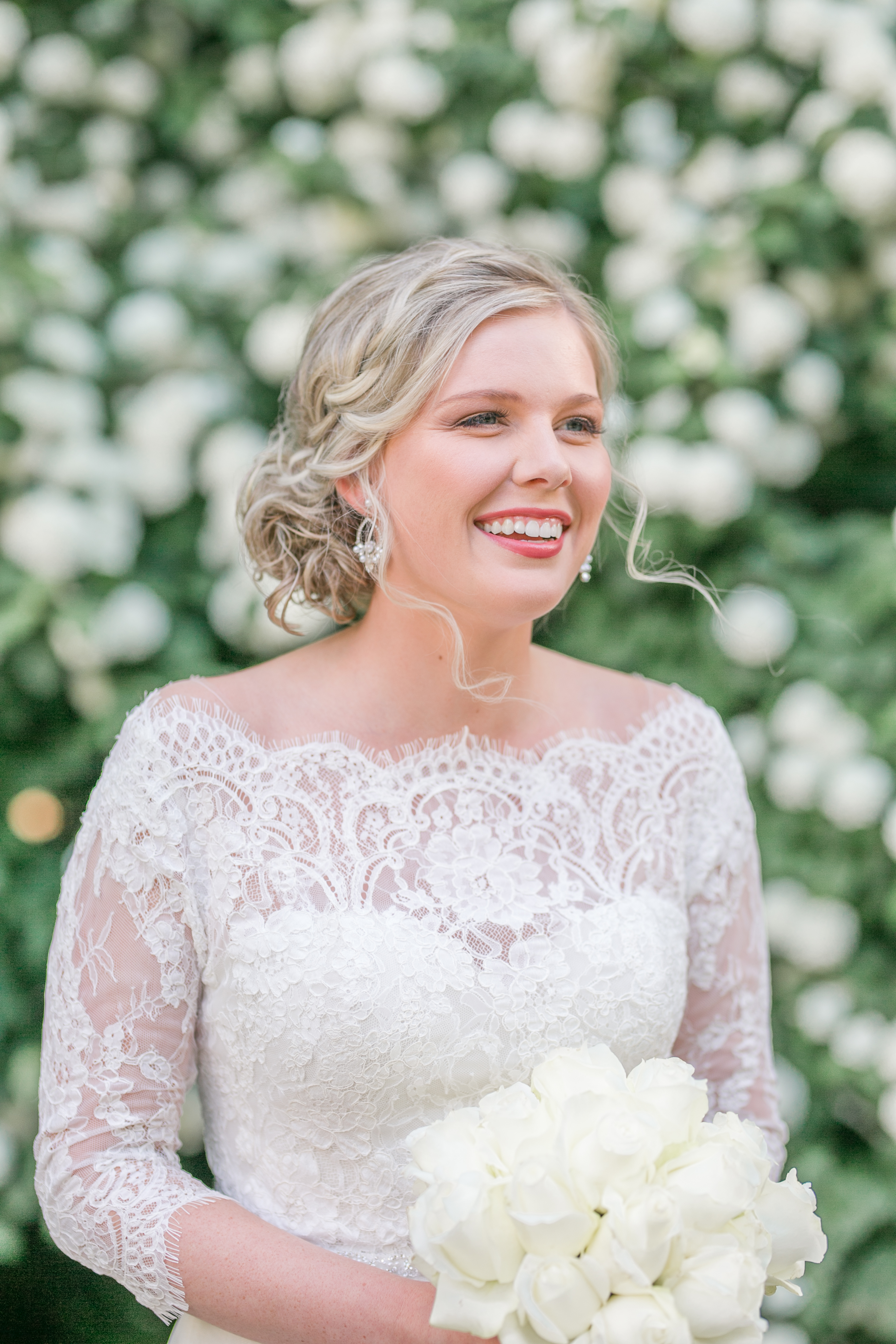 bride smiles off in distance in front of white blooming tree
