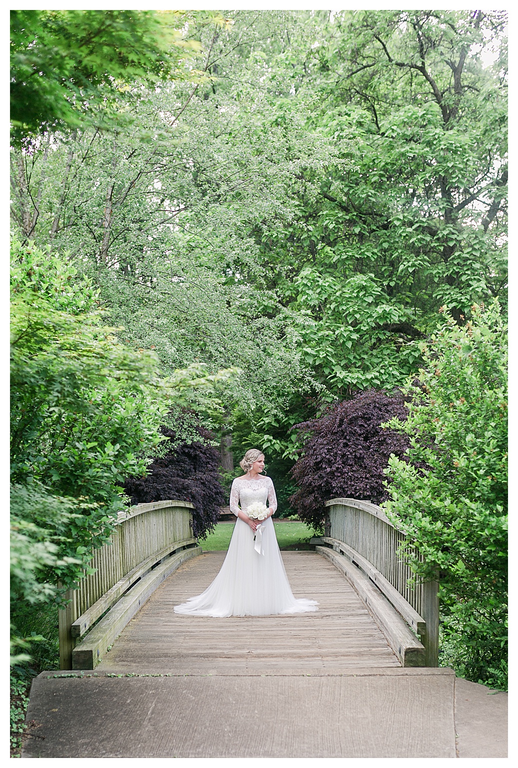 bridal portrait session, bride poses on wood bridge surrounded by green and purple foliage