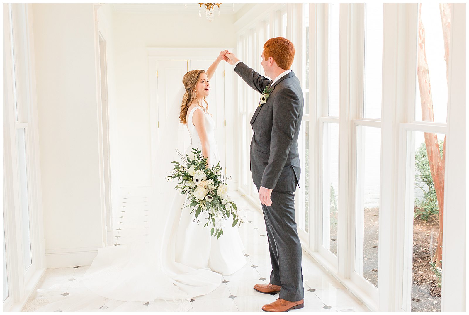 groom twirls bride during first look in beautifully lit hallway