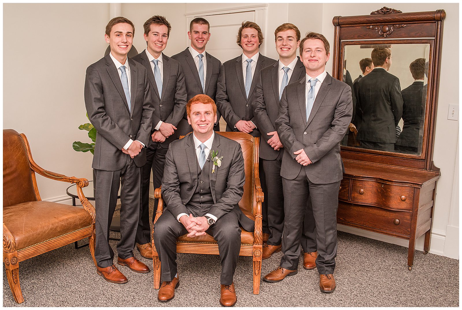 groom seated with groomsmen standing behind him, all smiling