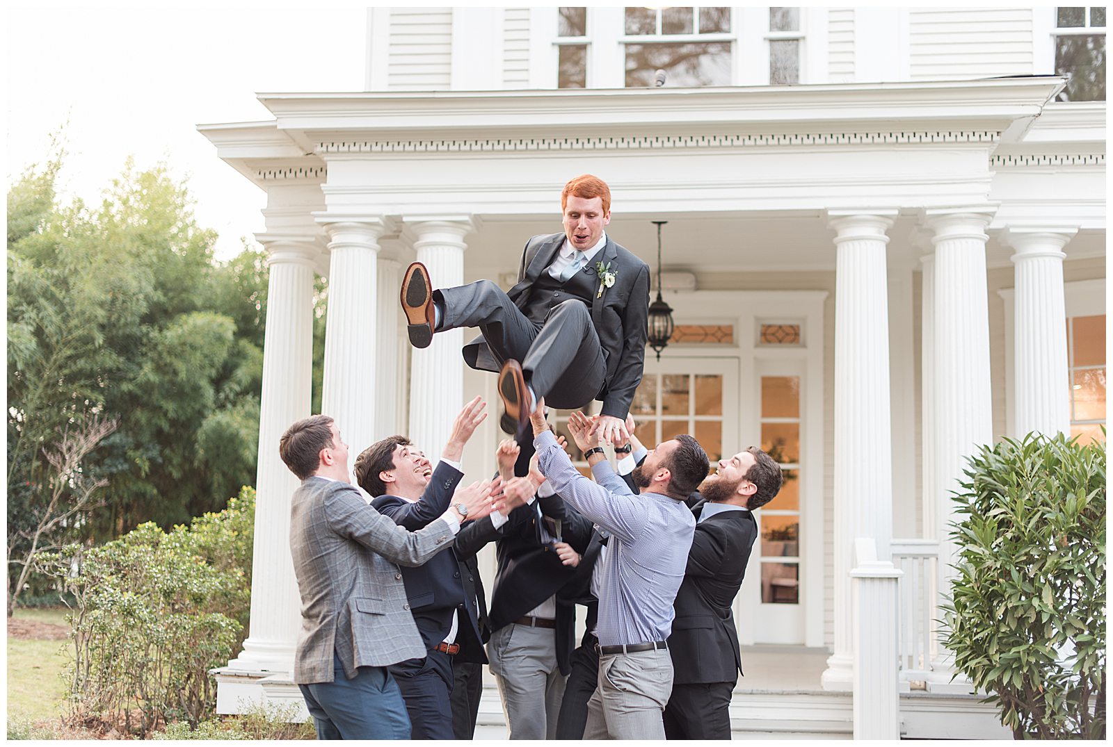 groom gets tossed in air by groomsmen and friends