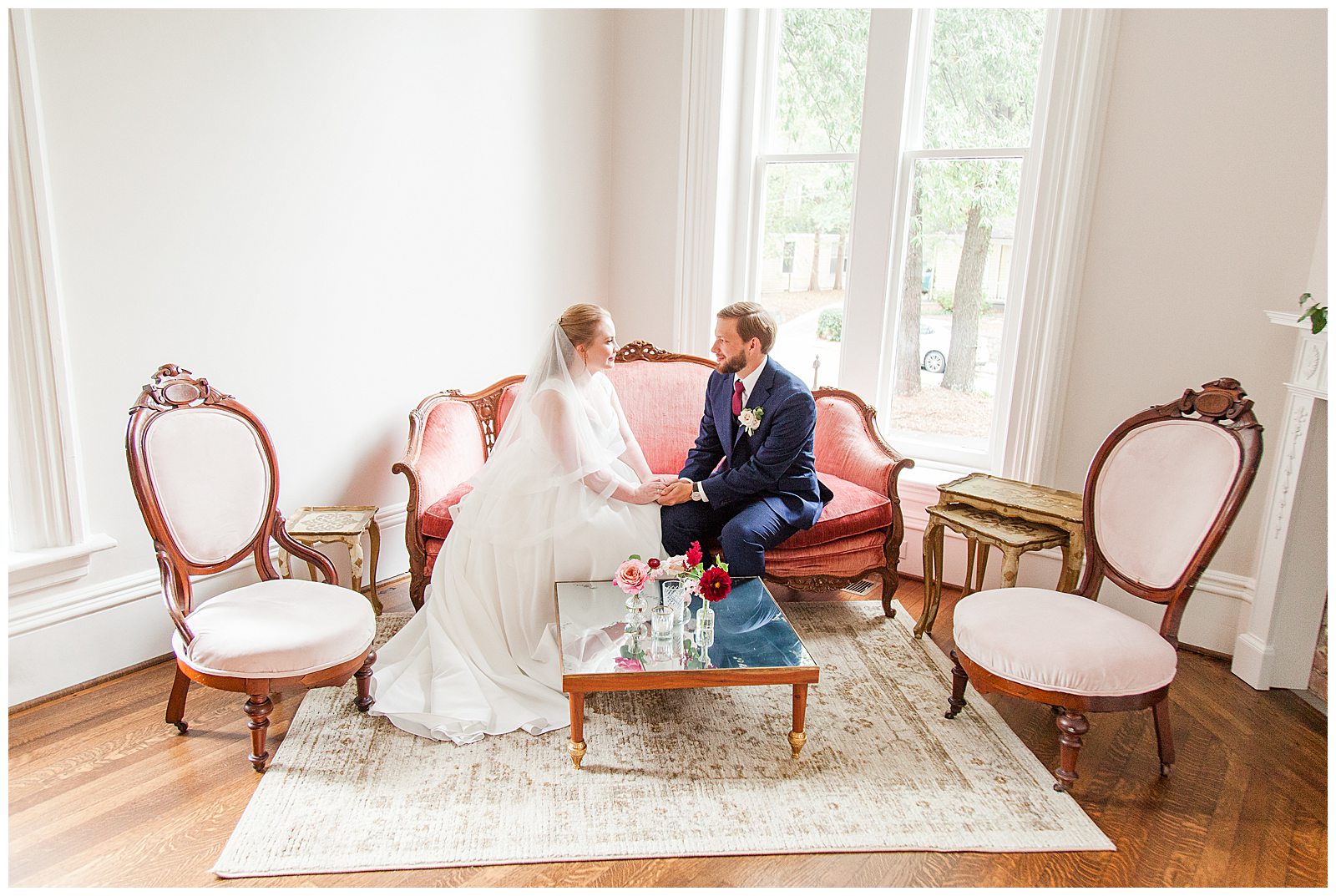 bride and groom sit in beautiful lounge with window light shining in
