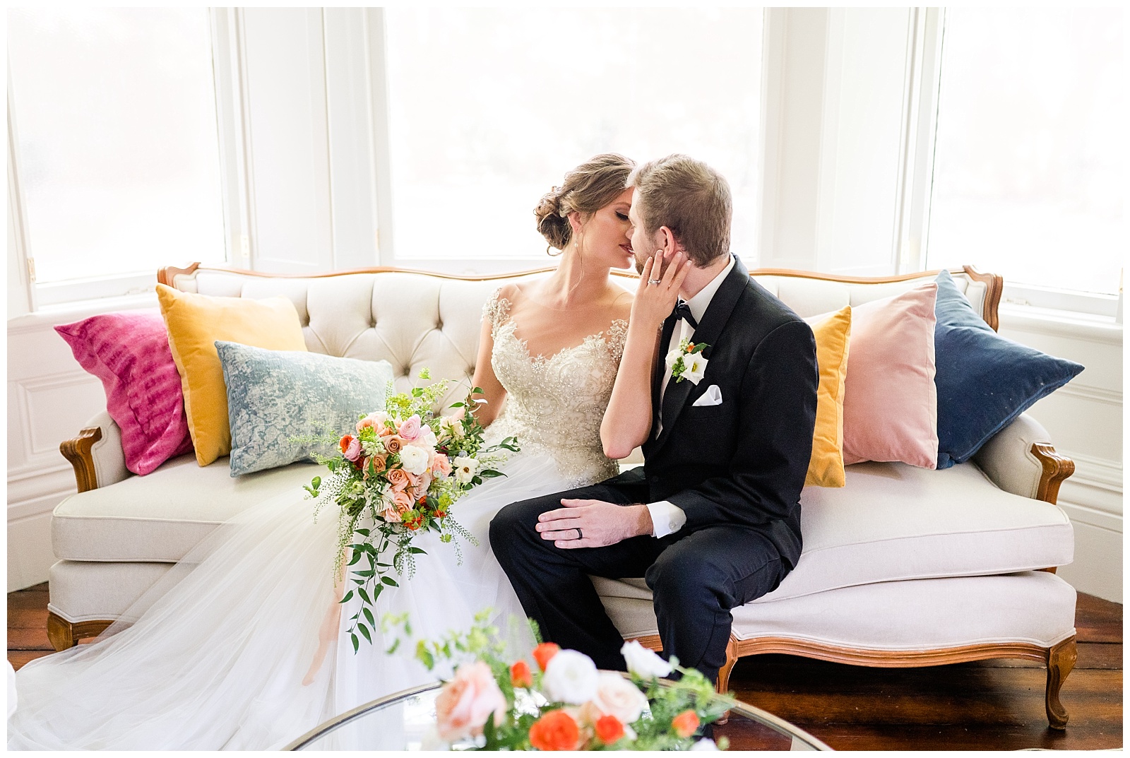 couple in wedding attire sitting on antique couch sharing a kiss during holt house nc styled micro wedding shoot