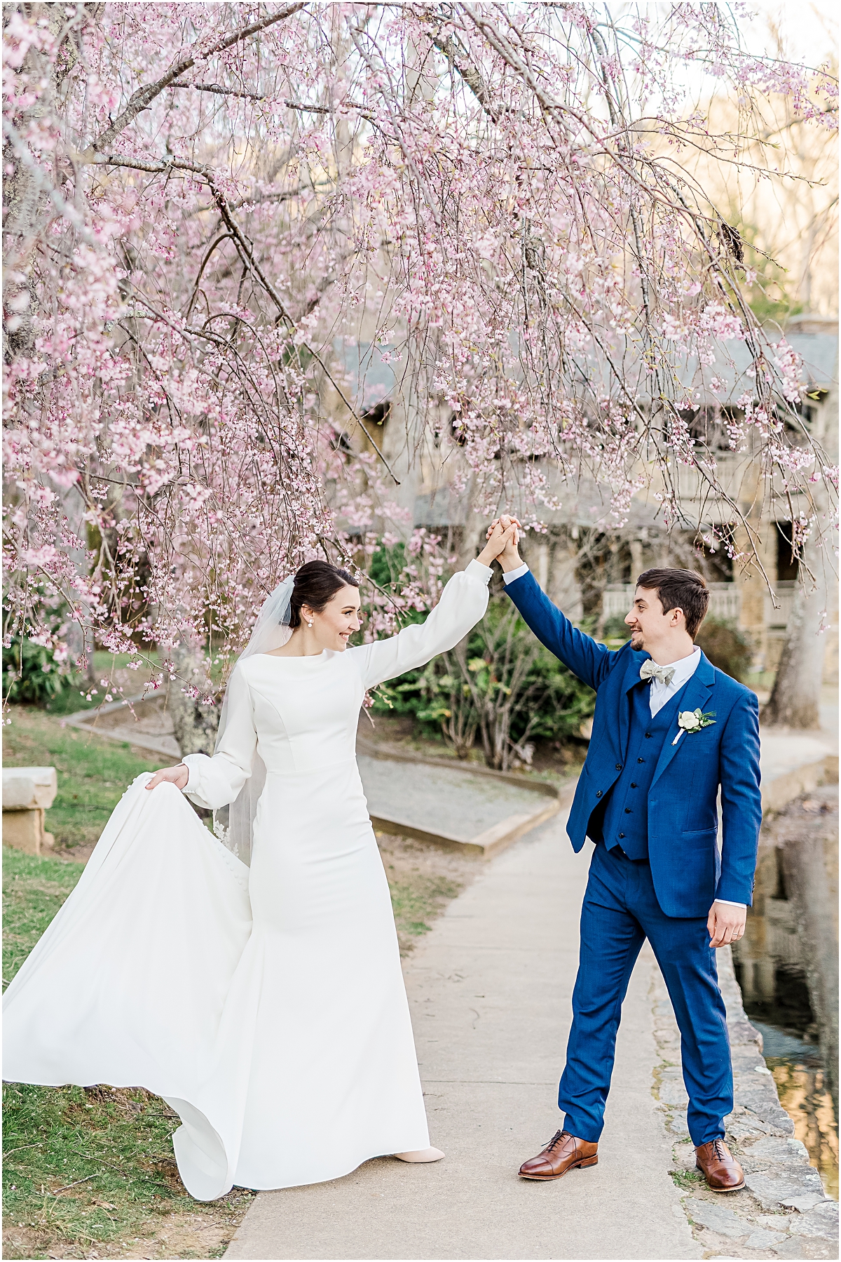 Grooms twirls bride under cherry blossom tree in North Carolina Mountains