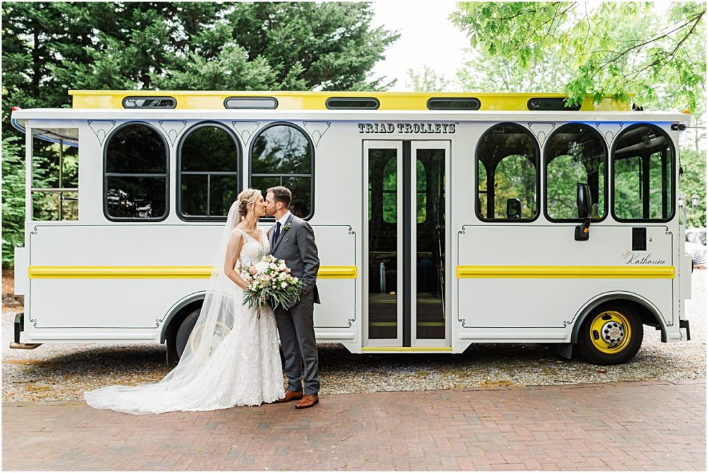 Amber and Chase kissing outside of their trolley during their Greensboro wedding