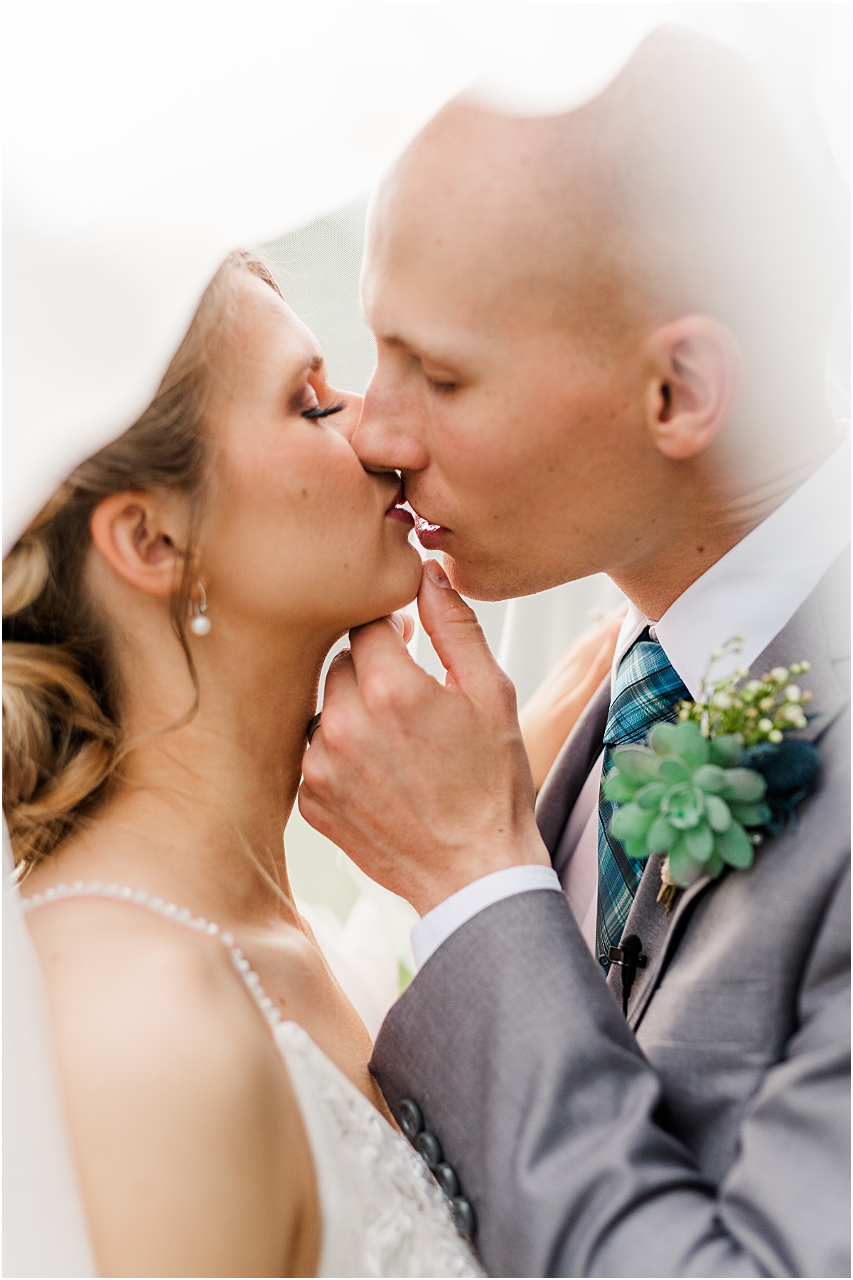 Luke and Brynn kissing under her veil taken by a wedding photographer