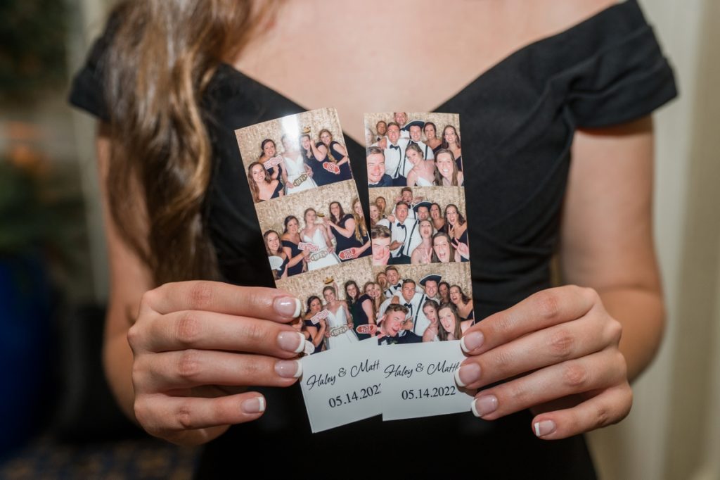 A wedding guest holding up two photo booth strips at Matt and Haley's Wedding in Raleigh NC