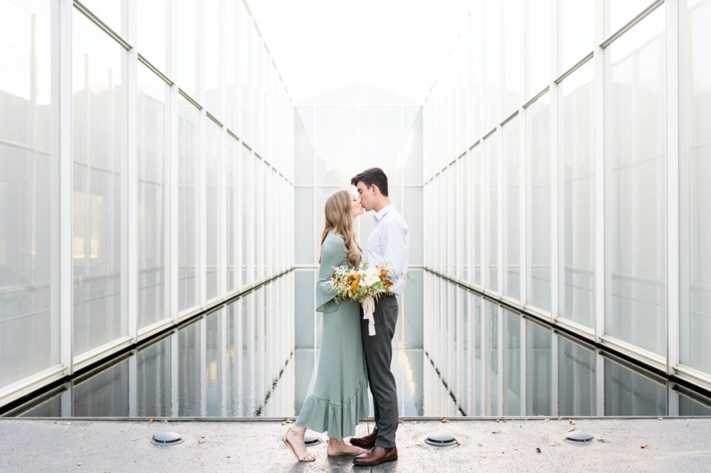 Couple kissing at the North Carolina Museum of Art during their engagement session with Jenn Eddine Photography.