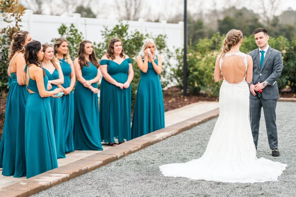 A bride and groom saying their vows at Board and Batten while the bridesmaids look on crying.