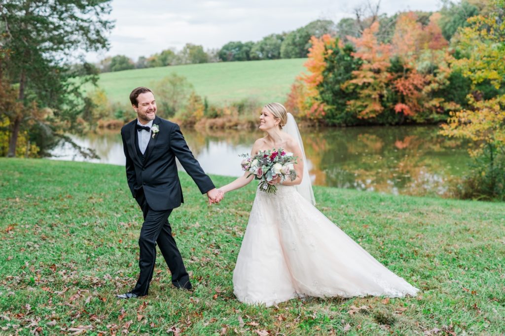A couple walking hand in hand in front of a pond on their wedding day designed by Katharine Mann Events.