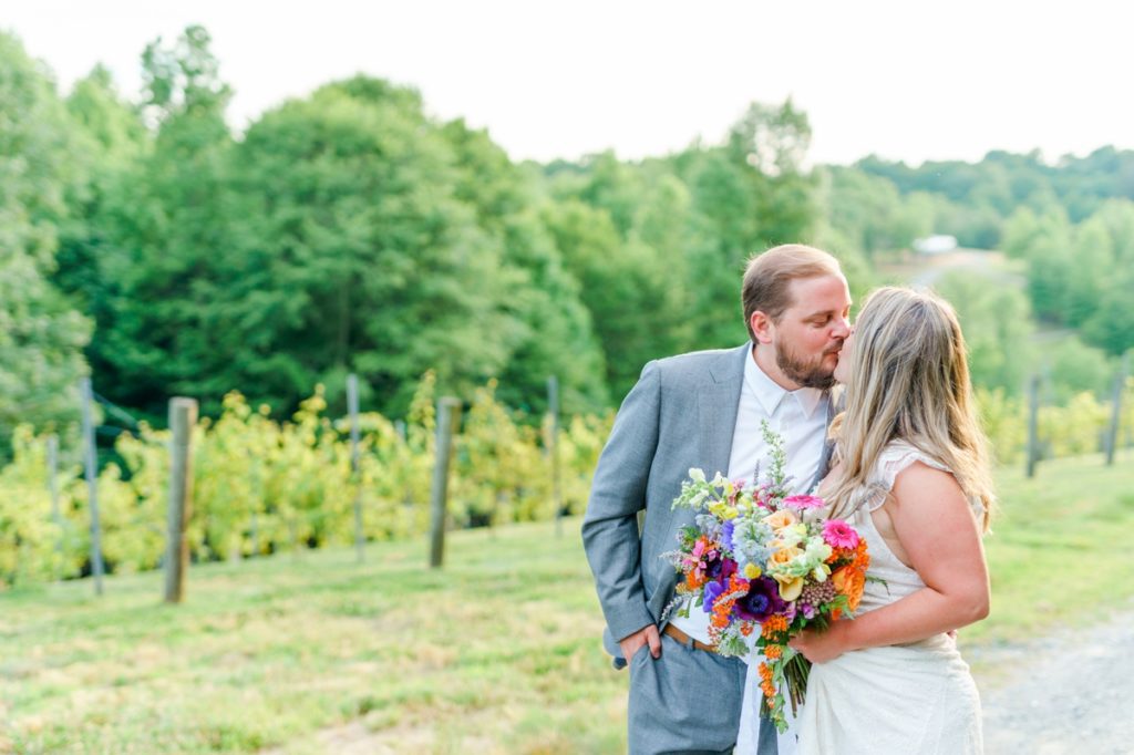 A bride and groom kissing in the vines at Medaloni Cellars on their wedding day.