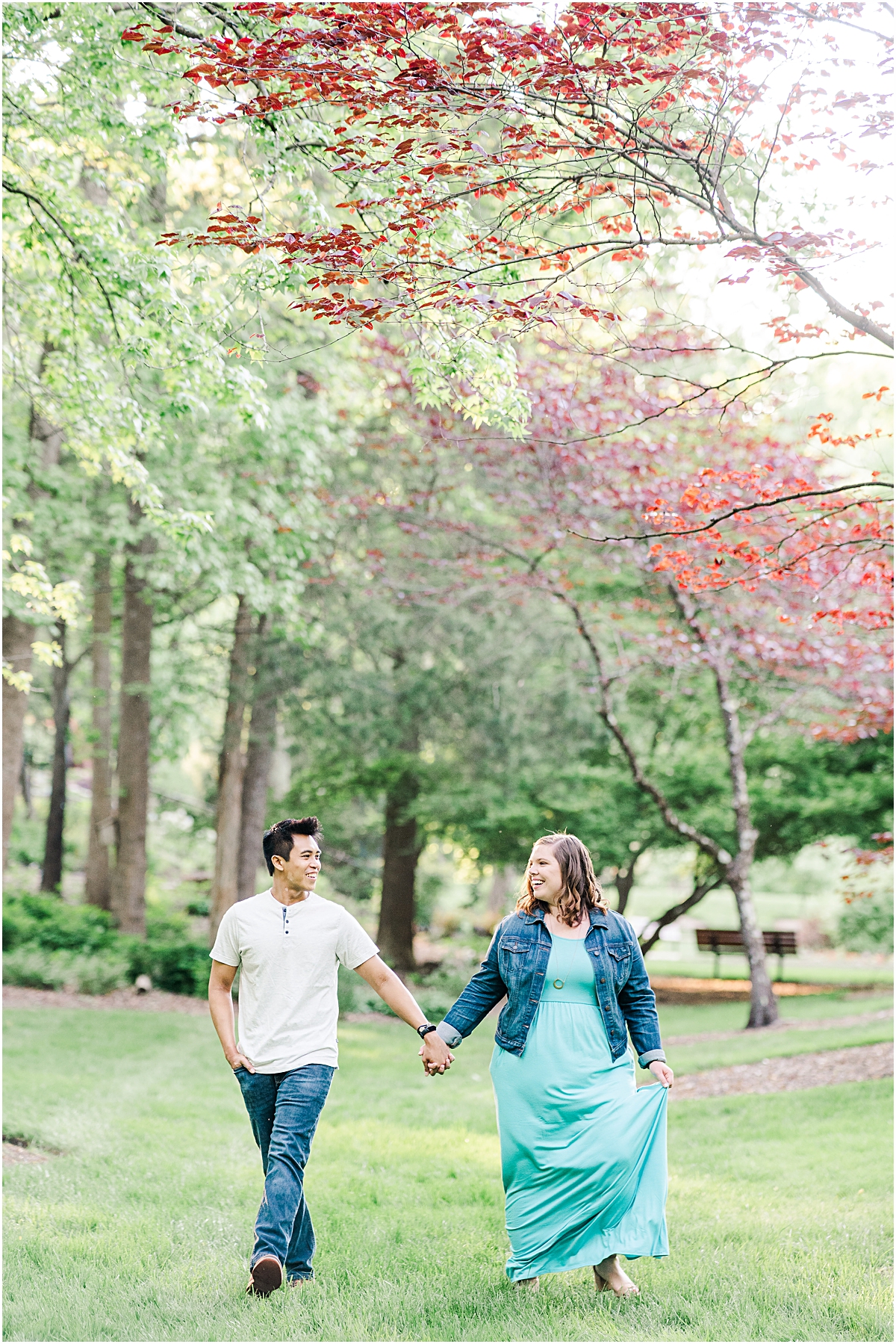 Couple holding hands and walking towards the camera smiling and laughing at each other during their Engagement session at Greensboro Arboretum