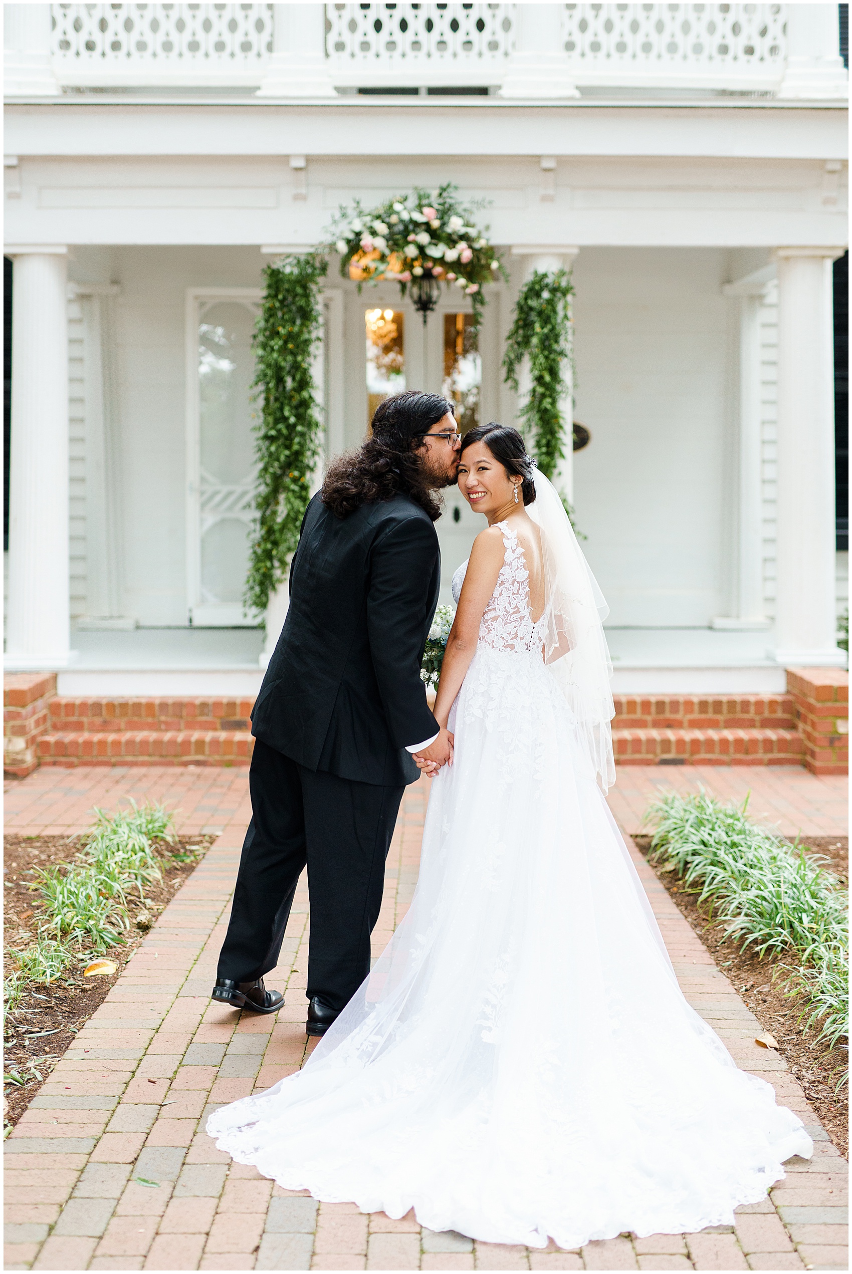 Groom kissing bride on the cheek in front of the A Stunning and Historic Leslie Alford Mims House Wedding Venue